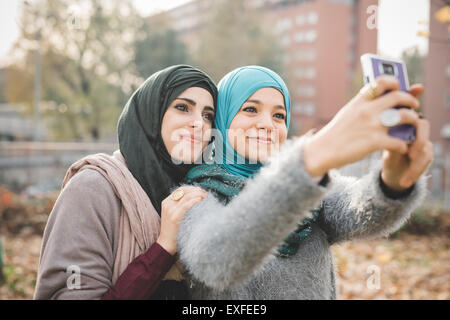 Two female friends in park posing for smartphone selfie Stock Photo