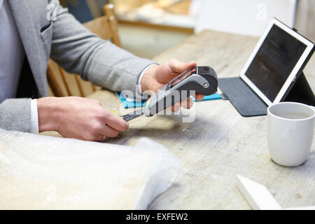 Man buying online with credit card in picture framers workshop Stock Photo