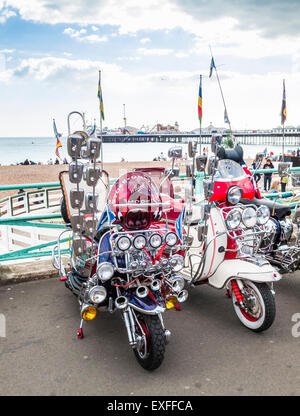 Vintage motor scooters from the Mods and Rockers era, with multiple headlights and wing mirrors, parked on Brighton seafront Stock Photo
