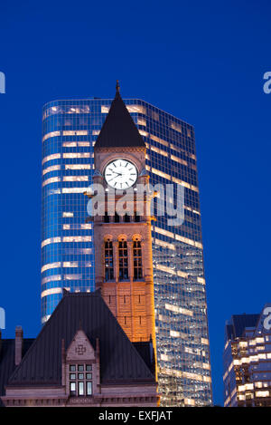 Detail of Toronto's city hall tower clock at dusk against modern building Stock Photo