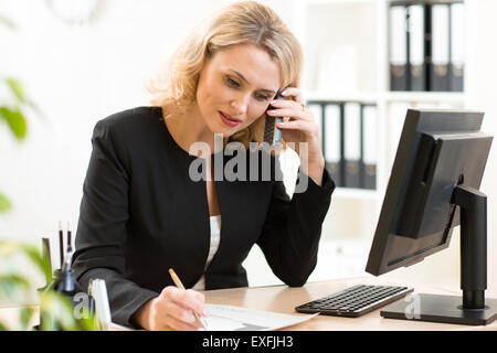 Middle-age businesswoman talking on the mobile phone in office. Portrait of smiling business woman. Stock Photo