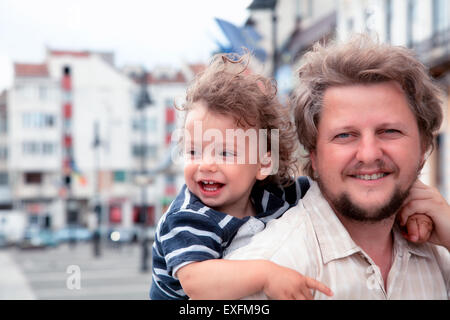 1 year old baby boy laughing while in daddy's back. Stock Photo