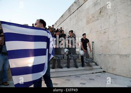 Athens, Greece. 13th July, 2015. A man holds a Greek flag in front of the Greek parliament during an anti-austerity rally in Athens, Greece, on July 13, 2015. © Marios Lolos/Xinhua/Alamy Live News Stock Photo