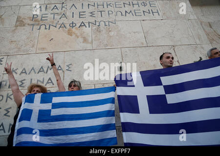 Athens, Greece. 13th July, 2015. Men hold Greek flags in front of the Greek parliament during an anti-austerity rally in Athens, Greece, on July 13, 2015. © Marios Lolos/Xinhua/Alamy Live News Stock Photo