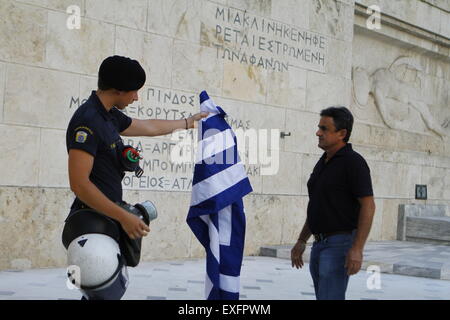 Athens, Greece. 13th July, 2015. A riot police officer returns the Greek flag to the protester. Greeks assembled outside the Greek Parliament under the banner of 'We leave this Europe'. They called for the government to not give into the demands of the Greek creditors for more austerity measures, but rather to leave the Eurozone. © Michael Debets/Pacific Press/Alamy Live News Stock Photo