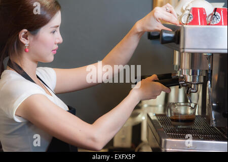 Female bartender makes coffee using coffee machine. Stock Photo