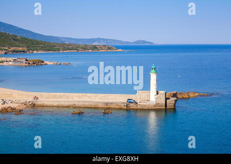 White lighthouse tower on stone pier. Entrance to Propriano port, Corsica, France Stock Photo