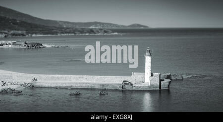 White lighthouse tower on the pier. Entrance to Propriano port, Corsica, France. Monochrome photo with shallow focus effect Stock Photo