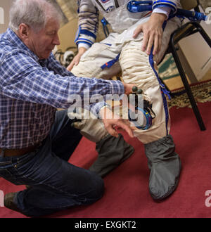 A technician places Russian sokol suit gloves in the NASA astronaut Kjell Lindgren's pockets as he and , Russian cosmonaut Oleg Kononenko, and Japan Aerospace Exploration Agency astronaut Kimiya Yui participate in the second day of qualification exams, Thursday, May 7, 2015 at the Gagarin Cosmonaut Training Center (GCTC) in Star City, Russia. The Expedition 44/45 trio is preparing for launch to the International Space Station in their Soyuz TMA-17M spacecraft from the Baikonur Cosmodrome in Kazakhstan. Stock Photo