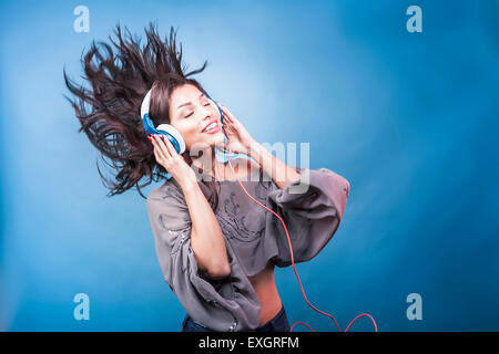 A young woman smiles, moves and wears headphones. Stock Photo