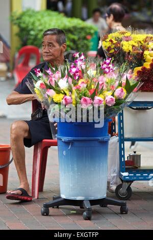 Old Oriental Man Selling Flowers Outside The Kwan Im Thong Hood Cho Temple In Waterloo Street, Singapore. Stock Photo