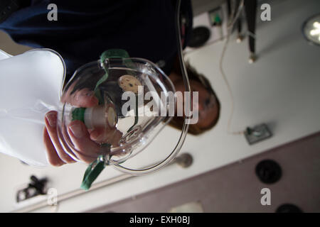 Female EMT giving patient oxygen in the back of an ambulance. Stock Photo