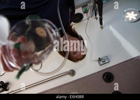 Female EMT giving patient oxygen in the back of an ambulance. Stock Photo