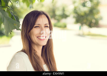 Young smiling woman with healthy teeth at sunny summer day. Pretty european girl with long hair. Warm color toned image
