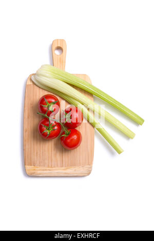 Fresh tomatoes and celery sticks on chopping board, top view isolated on white background Stock Photo