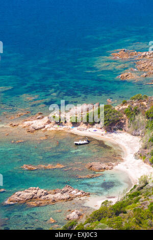 Corsica island, Cupabia gulf. Vertical coastal landscape with small motor boat near wild rocky beach Stock Photo