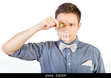 Young serious man in shirt and bow tie holds door locker. Male person holding key over white background. Stock Photo