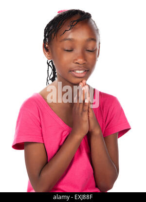 Adorable small african child with braids wearing a bright pink shirt. The girl is kneeling and praying. Stock Photo