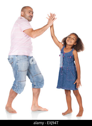 Adorable cute african child with afro hair wearing a denim dress is playing with her father. The dad is wearing a pink shirt and Stock Photo