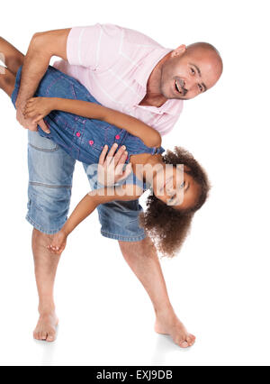 Adorable cute african child with afro hair wearing a denim dress is playing with her father. The dad is wearing a pink shirt and Stock Photo