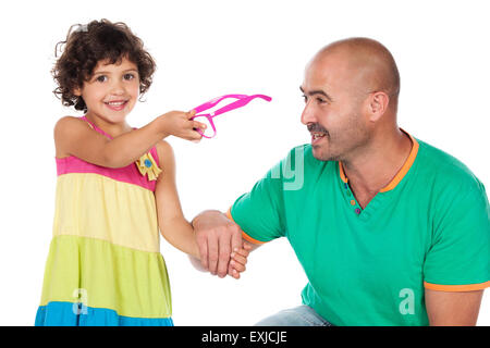 Adorable small caucasian child with curly hair wearing a pink blue and yellow dress. The girl and her father are playing with pi Stock Photo