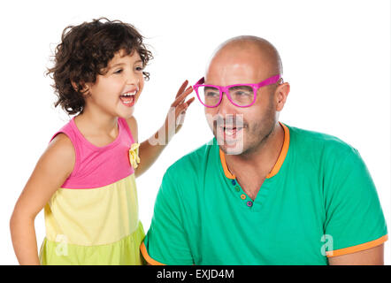 Adorable small caucasian child with curly hair wearing a pink blue and yellow dress. The girl and her father are playing with pi Stock Photo