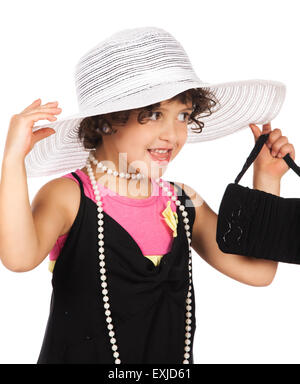 Adorable cute caucasian girl is playing dress up. She is wearing a black dress, white hat, earrings and coral high heel shoes. Stock Photo