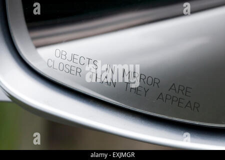 Objects in mirror are closer than they appear message in passenger side mirror of car - USA Stock Photo