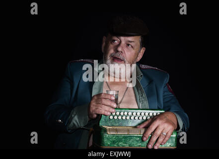 Portrait (low key) of an old retired military man who plays accordion for food and alcohol Stock Photo