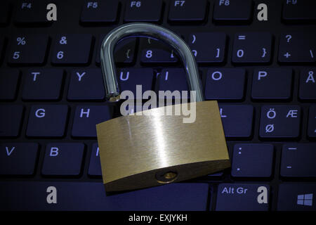 Close-up of a unlocked padlock on a computer keyboard with blue hue. Concept photo of technology, Internet and computer security Stock Photo