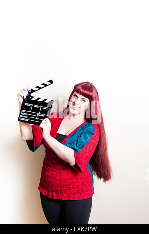 Young woman smiling showing movie clapper board on white background Stock Photo