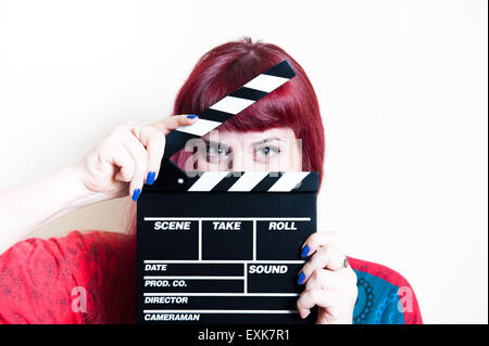 Young woman smiling showing movie clapper board on white background Stock Photo