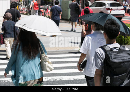 Pedestrians hold parasols to get some shade in the hot weather in Shinjuku district on July 15, 2015, Tokyo, Japan. Japan has been experiencing the hottest days of the year so far with temperatures reaching 35 degrees Celsius in Tokyo and a record 38.5 high for the year so far in Niigata. According to the Japanese Fire and Disaster Management Agency over 3000 people were treated nationwide for heat exhaustion in the week up to the 12th July. © Rodrigo Reyes Marin/AFLO/Alamy Live News Stock Photo