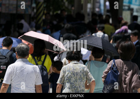 Pedestrians hold parasols to get some shade in the hot weather in Shinjuku district on July 15, 2015, Tokyo, Japan. Japan has been experiencing the hottest days of the year so far with temperatures reaching 35 degrees Celsius in Tokyo and a record 38.5 high for the year so far in Niigata. According to the Japanese Fire and Disaster Management Agency over 3000 people were treated nationwide for heat exhaustion in the week up to the 12th July. © Rodrigo Reyes Marin/AFLO/Alamy Live News Stock Photo