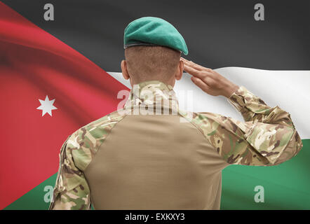Dark-skinned soldier in hat facing national flag series - Jordan Stock Photo