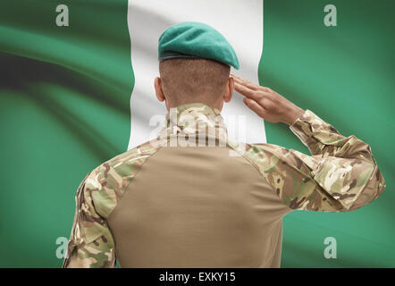 Dark-skinned soldier in hat facing national flag series - Nigeria Stock Photo