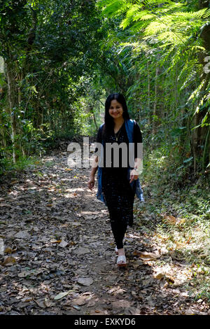 well dressed pretty local female walking along a muddy track amongst trees in java indonesia Stock Photo