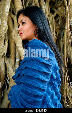 pretty well dressed local female posing in front of tree with large roots in a park in the center of malang java indonesia Stock Photo