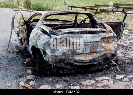 Burnt out rusted old car near the road Stock Photo