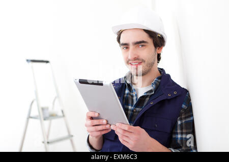 View of a Young worker man in a new flat using tablet Stock Photo