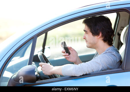 View of a Young man using his smartphone while driving Stock Photo