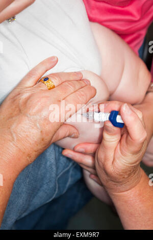 MMR etc immunisation / inoculation / jab / from a syringe into a one year old / 12 13  twelve thirteen month baby's thigh / leg. Stock Photo