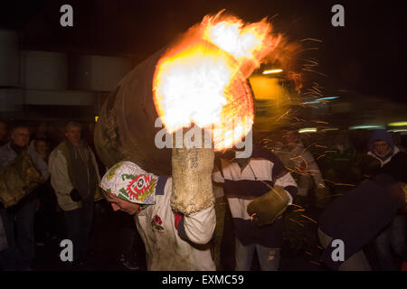 Intermediate burning barrel being carried through the street to mark Bonfire Night, 5 November, at the Tar Barrels festival, Ottery St Mary, Devon, England Stock Photo