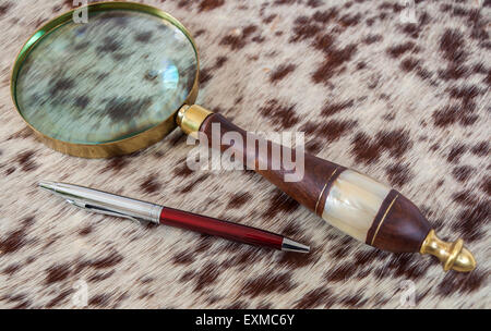 Old book with magnifying glass and a pen on a white background ...