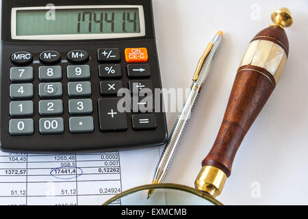 A Calculator,Pen And Magnifying Glass Sit On a Page With Numbers Stock Photo
