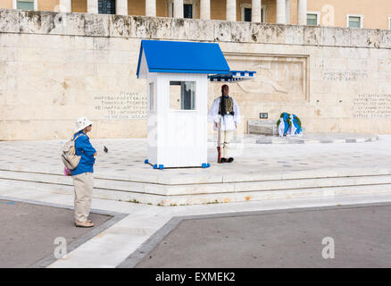 Lone tourist watches a Greek Evzone guard outside Parliament House and the Tomb of the Unknown Soldier, Athens, Greece Stock Photo