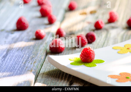 Rasberries on modern white plate isolated on wood background Stock Photo