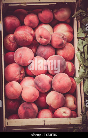 Fresh peaches selling in a market. Vertical filtered shot with a selective focus Stock Photo