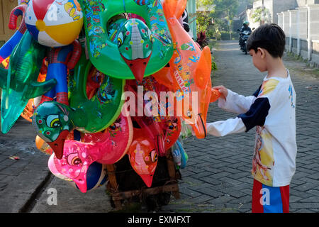 little boy looking at colourful toys being sold from a street vendors motorcycle Stock Photo