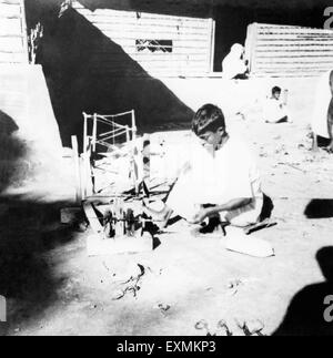 A young man spinning on a big size charkha spinning wheel effected by Hindu Muslim riots in Noakhali East Bengal Stock Photo